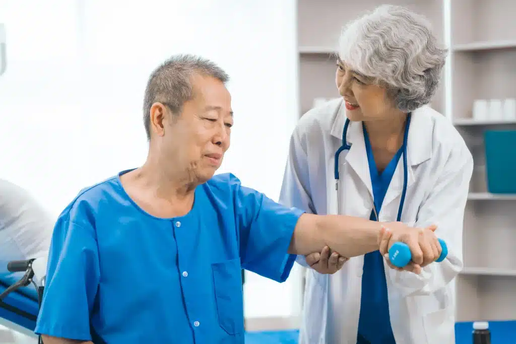 Elderly male patient receiving assistance from a doctor with physical therapy exercises for pain management.