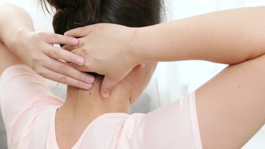 Back view of a woman massaging her neck to locate neck pain relief pressure points.