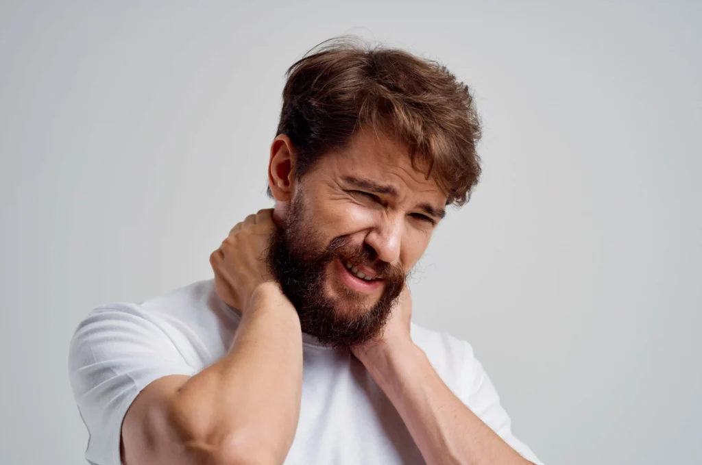 Man holding his neck in pain before trying McKenzie Method exercises for relief.