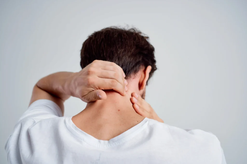 Man in a white shirt massaging his neck to activate pressure points for neck pain relief.