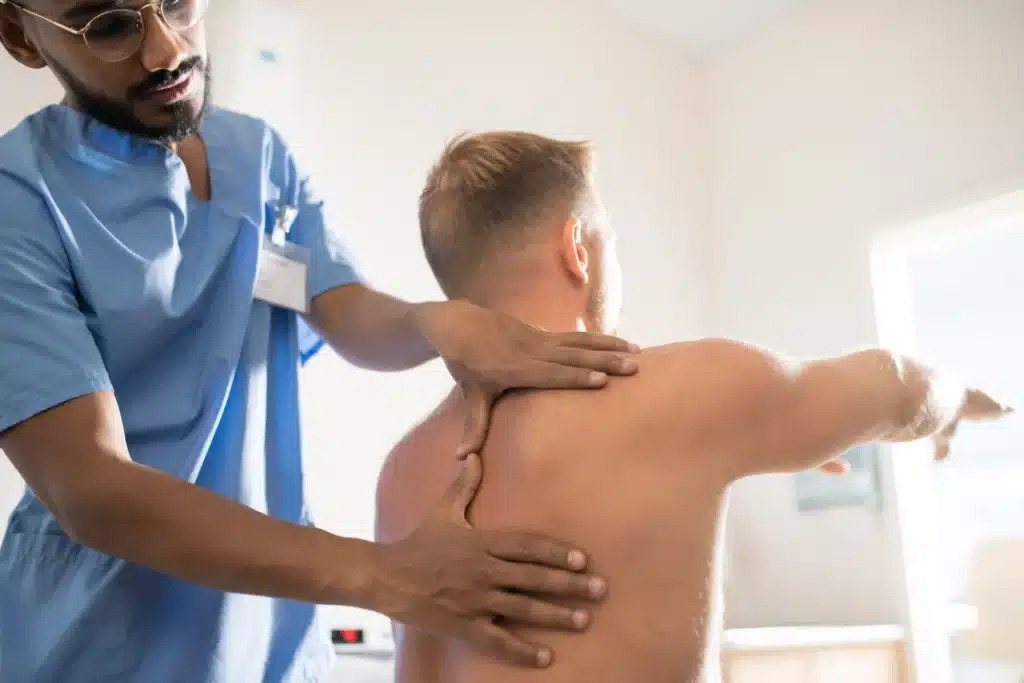 A medical specialist massaging a patient's shoulder, aiding recovery after spinal fusion surgery with rods and screws.