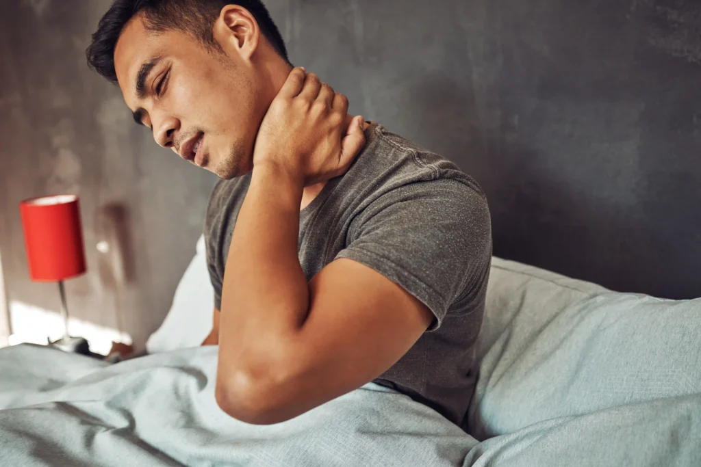 Young man holding his neck in pain after sleeping in a poor position.