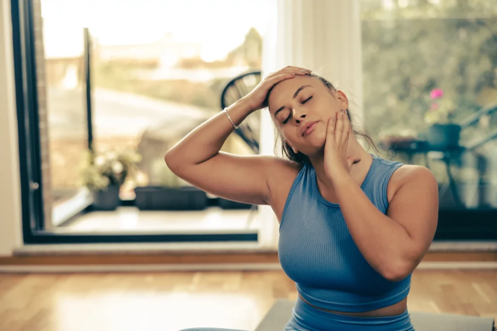 Woman performing yoga stretching exercises at home to ease neck pain as part of neck pain relief yoga.