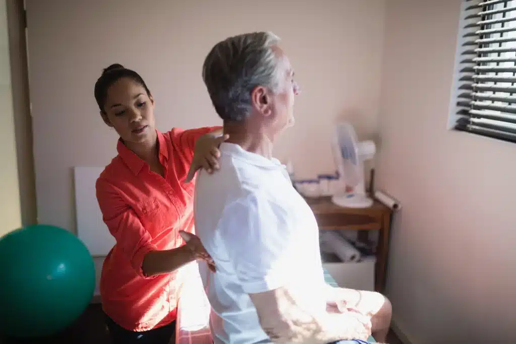 Female therapist providing back treatment to a senior man during a rehabilitation session."