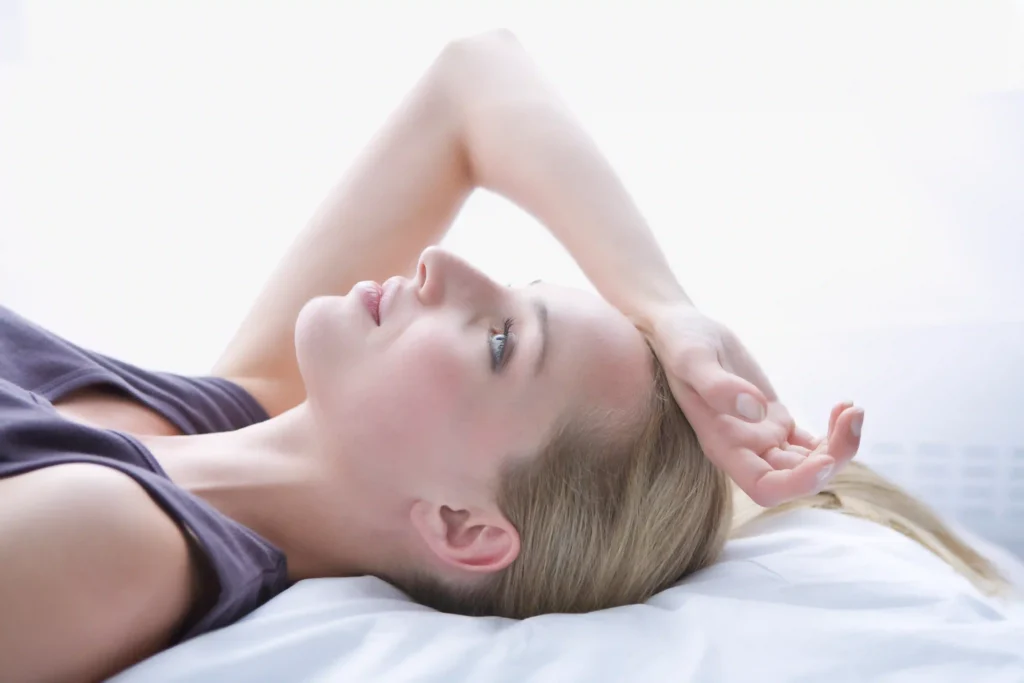 Young woman lying in bed, practicing proper neck pain relief sleeping positions.